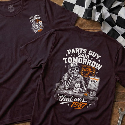 Dark t-shirt graphic with skeleton, calendar, and text "Parts Guy Said Tomorrow".