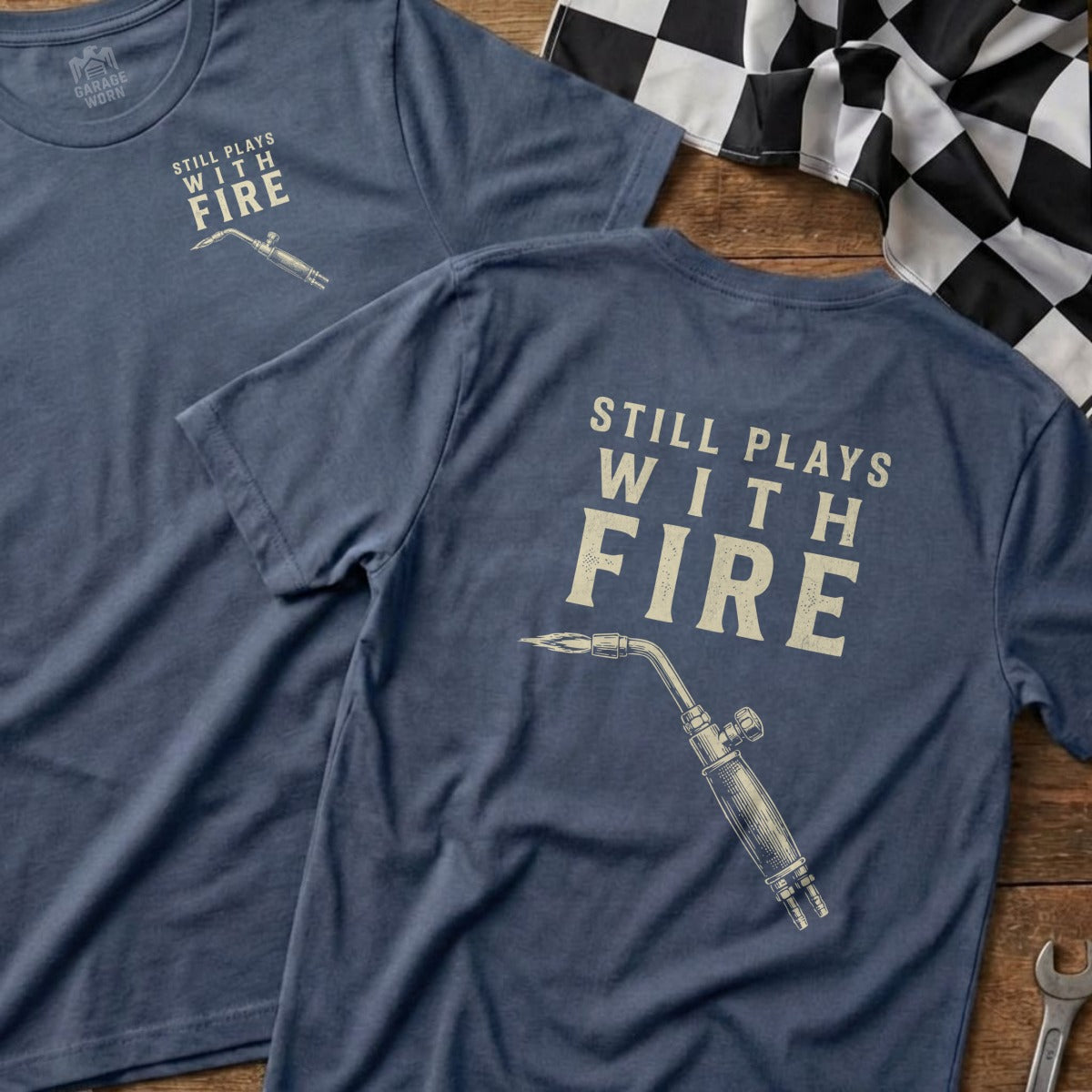 Navy t-shirt with "Still Plays With Fire" and a blowtorch graphic.