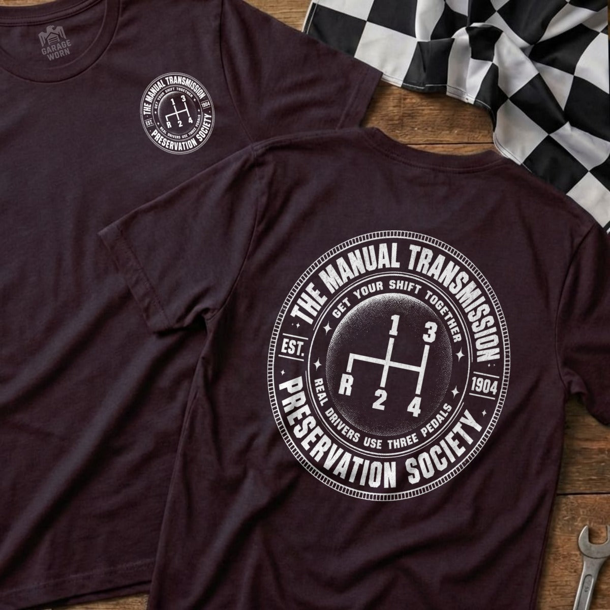 Dark t-shirt features a white graphic of a manual transmission shifter and "The Manual Transmission Preservation Society".