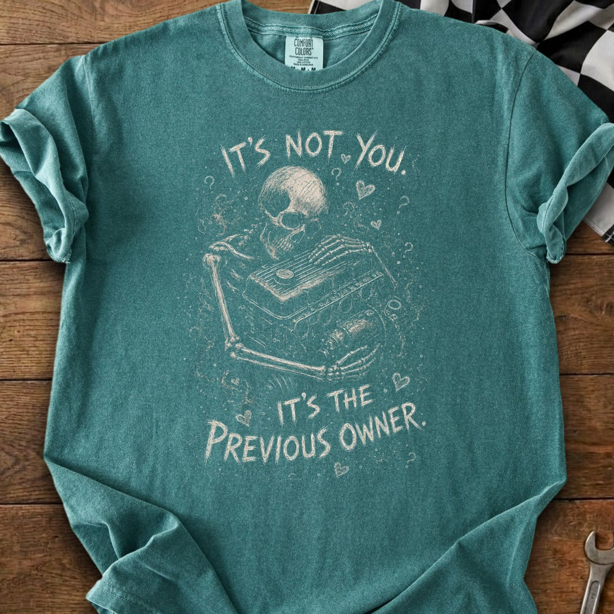 Teal t-shirt with skeleton holding engine parts, "It's not you. It's the previous owner."