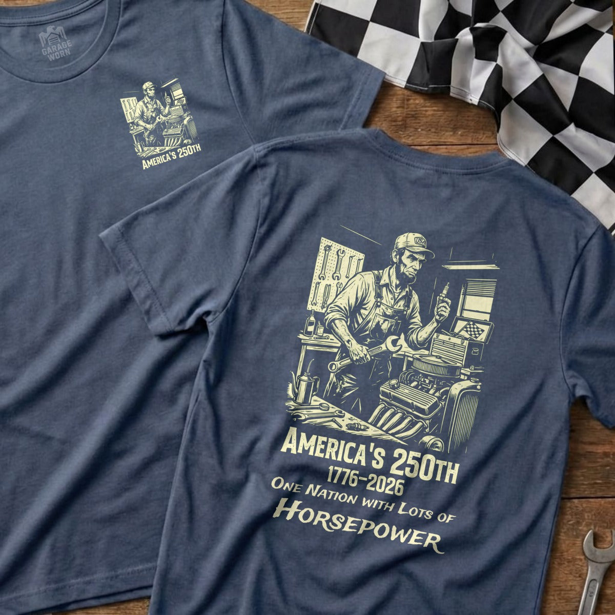 Blue t-shirt with graphic of mechanic and text "America's 250th One Nation with Lots of Horsepower".