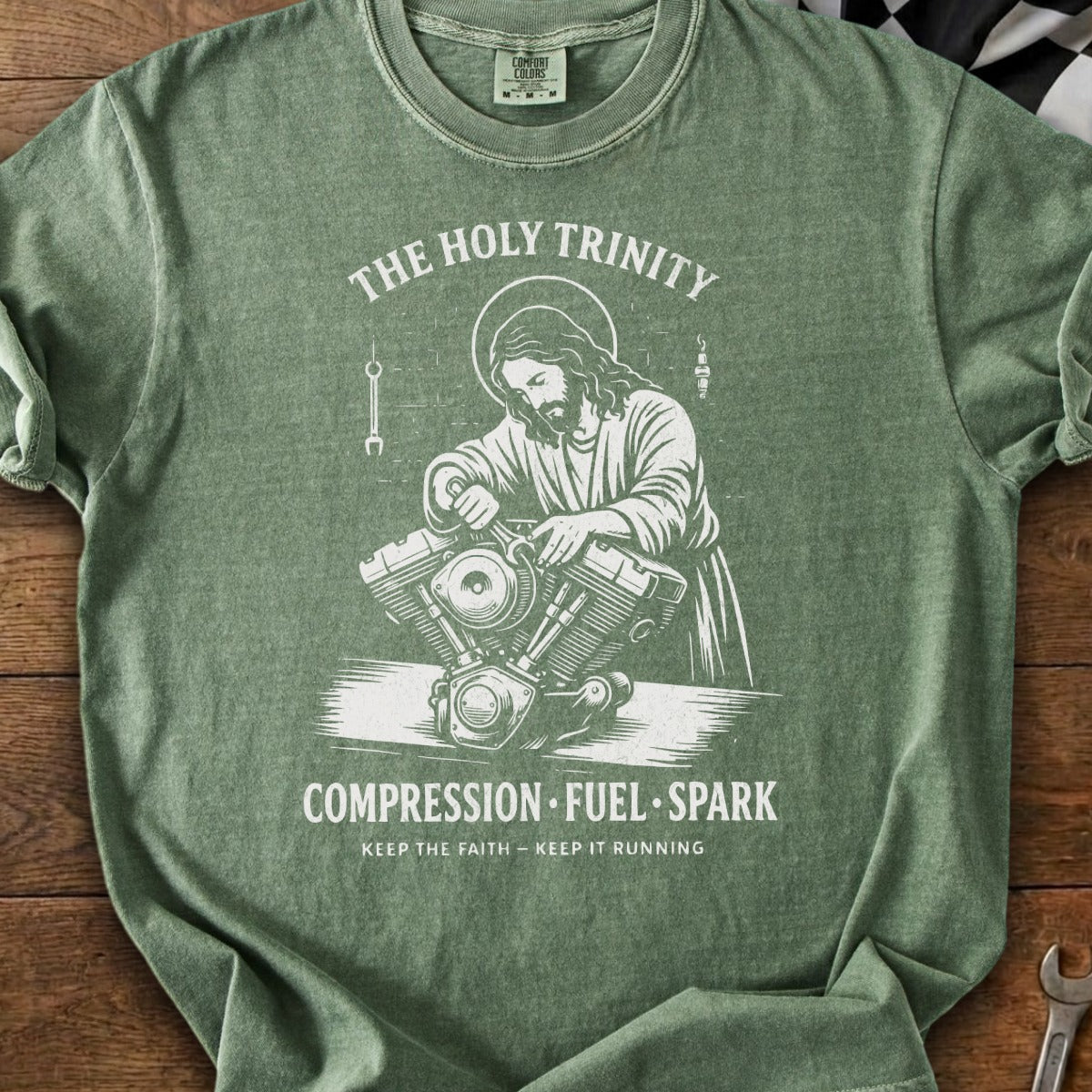 Jesus working on a motorcycle engine with text "The Holy Trinity" and "Compression Fuel Spark".