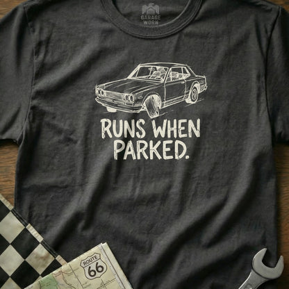 Dark t-shirt with white graphic of a classic car and text "RUNS WHEN PARKED."