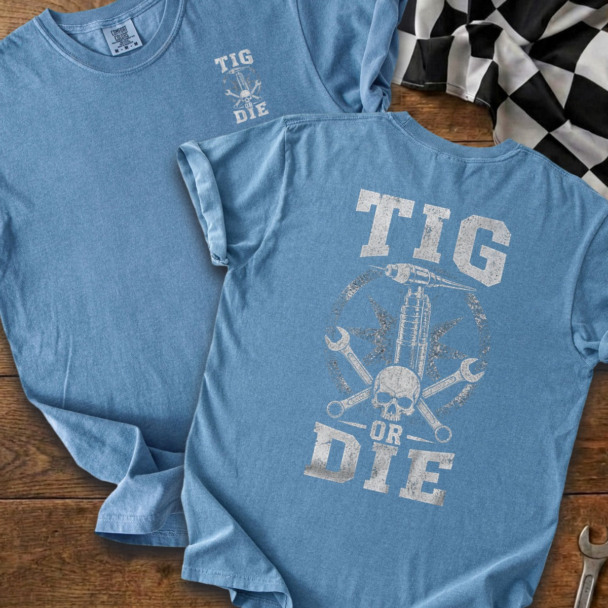 Blue t-shirt with "TIG OR DIE" graphic featuring a welding torch, skull, and wrenches.